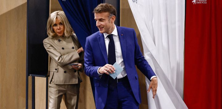 El presidente francés Emmanuel Macron y su esposa Brigitte Macron abandonan las cabinas de votación antes de emitir su voto en la primera ronda de las elecciones parlamentarias en una mesa electoral en Le Touquet, norte de Francia.