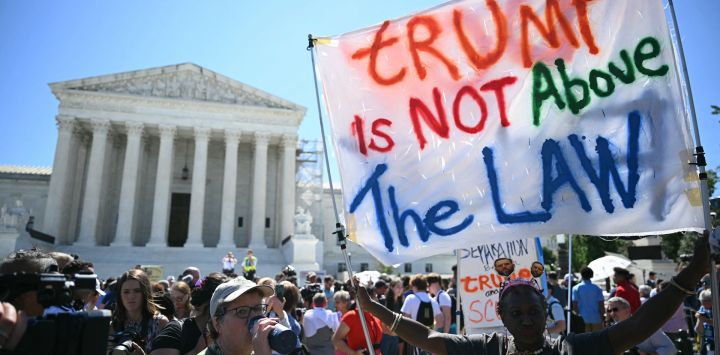 La gente sostiene carteles contra Trump frente a la Corte Suprema de Estados Unidos, en Washington, DC. Donald Trump elogió una "gran victoria" para la democracia después de que la Corte Suprema de Estados Unidos dictaminara que los presidentes tienen presunta inmunidad para actos oficiales, una decisión que retrasará su juicio por conspirar para revertir su derrota electoral de 2020.