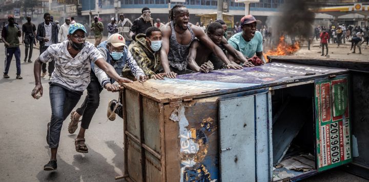 Los manifestantes corean consignas mientras utilizan mobiliario urbano como barricada para enfrentarse a los agentes de la policía de Kenia durante una manifestación antigubernamental convocada tras protestas mortales en todo el país por los aumentos de impuestos y un controvertido proyecto de ley de impuestos ahora retirado en el centro de Nairobi.