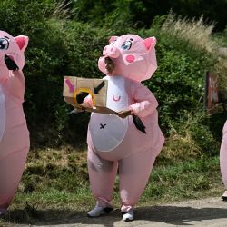 Espectadores disfrazados de cerdos inflables observan desde la carretera durante la sexta etapa de la 111ª edición de la carrera ciclista del Tour de Francia, 163,5 km entre Macon y Dijon. | Foto:MARCO BERTORELLO / AFP