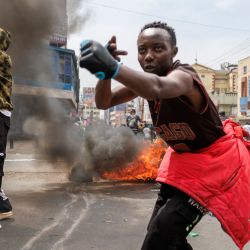 Los manifestantes hacen gestos a la policía antidisturbios de Kenia alrededor de una barricada en llamas durante una manifestación antigubernamental convocada luego de protestas mortales en todo el país por aumentos de impuestos y un controvertido proyecto de ley de impuestos ahora retirado en el centro de Nairobi. | Foto:TONY KARUMBA / AFP