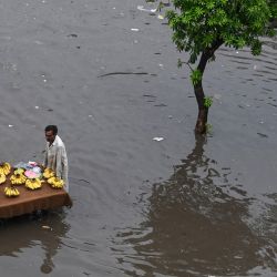Un vendedor de frutas empuja su carrito por una calle inundada después de las fuertes lluvias en Lahore, Pakistán. | Foto:Arif Ali / AFP