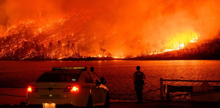 Los miembros de las fuerzas del orden observan cómo el incendio Thompson arde sobre el lago Oroville en Oroville, California. Una ola de calor está elevando las temperaturas, lo que ha provocado advertencias de incendio con bandera roja en todo el estado.