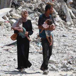Una pareja palestina sostiene a sus hijos mientras caminan entre escombros en Khan Yunis, en el sur de la Franja de Gaza, en medio del conflicto en curso entre Israel y el grupo militante palestino Hamas. | Foto:Bashar Taleb / AFP