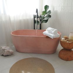 El baño de huéspedes es una de las estrellas de la casa. Con una bañera de Konqrit en color rosa viejo y detalle de bandeja y pedestal en madera.
