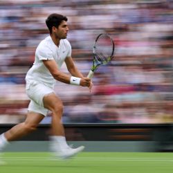 El español Carlos Alcaraz corre para jugar un tiro contra el francés Ugo Humbert durante su partido de tenis de cuarta ronda individual masculino en el séptimo día del Campeonato de Wimbledon 2024 en el All England Lawn Tennis and Croquet Club en Wimbledon, al suroeste de Londres. | Foto:HENRY NICHOLLS / AFP