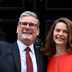 El primer ministro entrante de Gran Bretaña, Keir Starmer, y líder del Partido Laborista, y su esposa Victoria saludan mientras posan en las escaleras del número 10 de Downing Street en Londres, un día después de que Gran Bretaña celebrara elecciones generales. Starmer se convirtió en el nuevo primer ministro de Gran Bretaña, mientras su partido laborista de oposición de centro izquierda obtuvo una aplastante victoria en las elecciones generales, poniendo fin a 14 años de gobierno conservador de derecha. | Foto:JUSTIN TALLIS / AFP