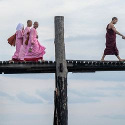 Esta foto muestra a un monje budista caminando frente a monjas en el puente U Bein en el lago Taungthaman en Mandalay, Myanmar. | Foto:Sai Aung Principal / AFP