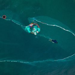 Esta fotografía aérea muestra a un hombre clasificando su red de pesca en el pueblo costero de Nhon Hai, cerca de Quy Nhon, en la provincia vietnamita de Binh. | Foto:DALE DE LA REY / AFP