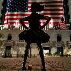 La Chica Intrépida se recorta por la noche frente a la Bolsa de Valores de Nueva York en Manhattan, Nueva York. | Foto:JUAN MABROMATA / AFP