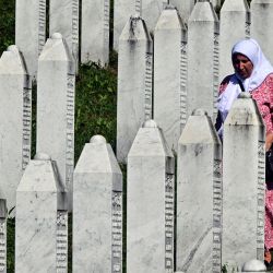 La sobreviviente musulmana bosnia del genocidio de Srebrenica de 1995, camina entre lápidas mientras visita las tumbas de sus familiares en el cementerio conmemorativo en la aldea de Potocari, cerca de la ciudad de Srebrenica, en el este de Bosnia. | Foto:ELVIS BARUKCIC / AFP