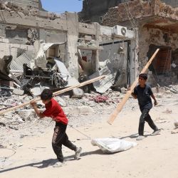 Los niños palestinos recogen leña para cocinar mientras avanzan sobre los sucios escombros, pasando por edificios destruidos después de que el ejército israelí se retirara tras una ofensiva de dos semanas desde el barrio de Shujaiya, al este de la ciudad de Gaza, en medio de la actual conflicto entre Israel y el grupo militante Hamás. | Foto:OMAR AL-QATTAA / AFP