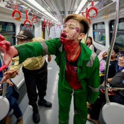 Los pasajeros ven a un artista actuar como un zombi en un vagón de tren durante el evento "Train to Apocalypse" como parte del Pandora Box Artmire Festival 2024, en Yakarta, Indonesia. | Foto:BAY ISMOYO / AFP