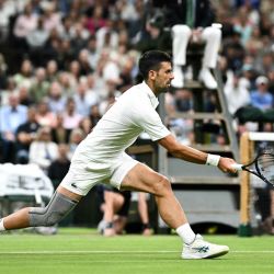 Novak Djokovic de Serbia devuelve la pelota a Holger Rune de Dinamarca durante su partido de tenis individual masculino en el octavo día del Campeonato de Wimbledon de 2024 en el All England Lawn Tennis and Croquet Club en Wimbledon, al suroeste de Londres. | Foto:Ben Stansall / AFP