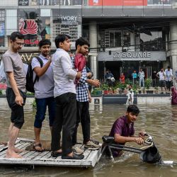 Las personas que viajan en un carro de tres ruedas viajan por una carretera inundada después de las fuertes lluvias en Dhaka, Bangladesh. | Foto:MUNIR UZ ZAMAN / AFP