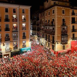 Los juerguistas levantan sus pañuelos rojos y velas mientras cantan la canción "Pobre de Mi", que marca el final del festival de San Fermín después del desfile de "Gigantes y Cabezudos" en Pamplona. | Foto:ANDER GILLENEA / AFP