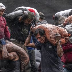 Buscadores de esmeraldas cargan sacos de tierra ya descartados por la multinacional Esmeraldas Mining Services (EMS) para buscar gemas verdes en el río Las Ánimas en Muzo, departamento de Boyacá, Colombia. | Foto:LUIS ACOSTA/AFP