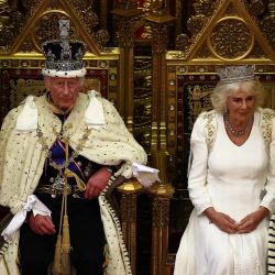 El rey Carlos III de Gran Bretaña, con la corona imperial y la túnica de Estado, se sienta junto a la reina Camilla de Gran Bretaña, con la diadema estatal de Jorge IV, antes de leer el discurso del rey desde el Trono del Soberano en la cámara de los Lores, durante la inauguración estatal del Parlamento, en Londres. | Foto:HENRY NICHOLLS/POOL/AFP