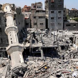 Hombres se encuentran ante el minarete derrumbado de una mezquita tras el bombardeo israelí en Nuseirat, en el centro de la Franja de Gaza, en medio del conflicto en curso en el territorio palestino entre Israel y Hamás. | Foto:Eyad Baba / AFP