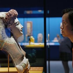 Imagen de una visitante observando una máscara facial de una momia femenina durante una vista previa para los medios de comunicación de la exposición "En la cima de la pirámide: La civilización del Antiguo Egipto" en el Museo de Shanghai, en Shanghai, en el este de China. | Foto:Xinhua/Liu Ying
