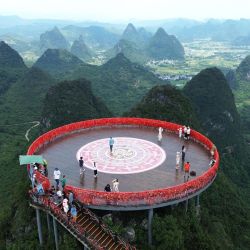 Vista aérea tomada con un dron de turistas disfrutando el paisaje montañoso en una plataforma de observación, en el distrito de Yangshuo, en la ciudad de Guilin, en el sur de China. Muchos destinos turísticos a lo largo de China han visto recientemente un incremento en visitantes mientras el país entra a su temporada alta de turismo de verano. | Foto:Xinhua/Liao Zuping