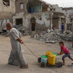 Los palestinos tiran de un carro con contenedores de agua que rellenaron desde un punto de suministro cercano en Khan Yunis, en el sur de la Franja de Gaza, en medio del conflicto en curso entre Israel y el grupo militante palestino Hamas. | Foto:Bashar Taleb / AFP