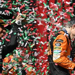 El piloto australiano ganador de McLaren, Oscar Piastri, es rociado con champán por el piloto británico de Mercedes, tercer clasificado, Lewis Hamilton, en el podio después del Gran Premio de Hungría de Fórmula Uno en el circuito de carreras de Hungaroring en Mogyorod, cerca de Budapest. | Foto:ATILA KISBENEDEK / AFP