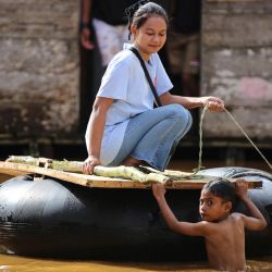 Una mujer viaja en una cámara de aire inflada en la zona afectada por las inundaciones después de que el río Kobe se desbordara tras las fuertes lluvias en Lukulamo, en el norte de Maluku, Indonesia. | Foto:Azzam Risqullah / AFP