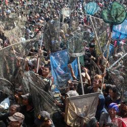 La gente intenta capturar unas dos toneladas de pescado liberadas por la ciudad durante un evento anual para agradecer la cosecha pesquera de este año en el embalse de Gemblegan en Klaten, Java Central, Indonesia. | Foto:DEVI RAHMAN / AFP