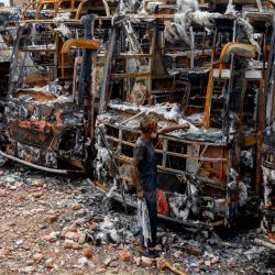 Un hombre observa vehículos quemados después de que los estudiantes les prendieron fuego durante las protestas contra el controvertido sistema de cuotas para los solicitantes de empleo en el gobierno, en Dhaka, Bangladesh. | Foto:K M ASAD / AFP