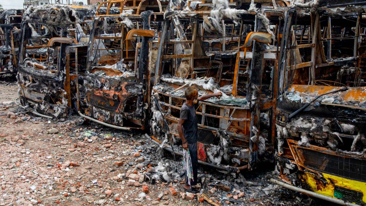 Un hombre observa vehículos quemados después de que los estudiantes les prendieron fuego durante las protestas contra el controvertido sistema de cuotas para los solicitantes de empleo en el gobierno, en Dhaka, Bangladesh. | Foto:K M ASAD / AFP