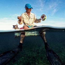 Un pescador cubano se prepara para pescar en una balsa improvisada en la Bahía de La Habana. Cuando el tiempo lo permite, los pescadores artesanales se lanzan al agua en improvisadas balsas de poliestireno para suplir la falta de medios y combustible. | Foto:YAMIL LAGE / AFP