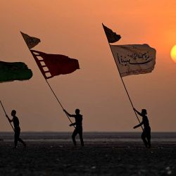 Peregrinos musulmanes chiíes levantan pancartas mientras caminan por la orilla fangosa del Golfo al comienzo de su marcha desde la ciudad de al-Faw, en el sur de Irak. Foto de Hussein FALEH / AFP | Foto:AFP