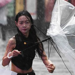Una mujer sostiene un paraguas roto afuera de un centro comercial durante una lluvia en Beijing. Foto de GREG BAKER / AFP | Foto:AFP