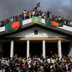 Manifestantes antigubernamentales exhiben la bandera nacional de Bangladesh mientras asaltan el palacio de la primera ministra Sheikh Hasina en Dhaka. El jefe del ejército de Bangladesh, Waker-Uz-Zaman, pasó casi cuatro décadas ascendiendo a la cima del ejército y dijo el 5 de agosto que estaba "asumiendo toda la responsabilidad" después de que la primera ministra Sheikh Hasina fuera derrocada y huyera. | Foto:K M ASAD / AFP