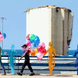Jóvenes vendedores ambulantes de globos pasan junto a figuras esculpidas que representan a personas que contemplan la devastación en una acera con vistas al puerto de Beirut. Cientos de personas se reunieron cerca del puerto de Beirut para conmemorar los cuatro años desde que una catastrófica explosión, una de las mayores explosiones no nucleares de la historia, devastó la capital del Líbano, que mató a más de 220 personas, hirió al menos a 6.500 y devastó zonas de la capital. | Foto:Ibrahim Amro / AFP