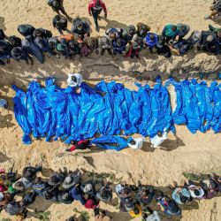 Una vista aérea muestra a los dolientes observando cómo el personal médico prepara los cuerpos de 47 palestinos, que fueron capturados y luego liberados por Israel, durante un funeral masivo en Rafah, en el sur de la Franja de Gaza, en medio de batallas en curso entre Israel y Hamás. | Foto:SAID KHATIB / AFP