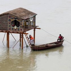 Los hombres reman en un bote cerca de una choza de paja inundada en el río Ganges en Prayagraj, después del aumento del nivel del agua durante los monzones. | Foto:SANJAY KANOJIA / AFP