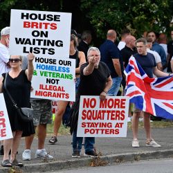 Manifestantes sostienen carteles durante una manifestación convocada por activistas de extrema derecha cerca de un hotel que alberga a solicitantes de asilo en Aldershot. Manifestantes de extrema derecha se enfrentaron con la policía británica durante tensas manifestaciones mientras los disturbios relacionados con la desinformación sobre un apuñalamiento masivo que mató a tres niñas se extendían por todo el Reino Unido. | Foto:JUSTIN TALLIS / AFP