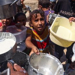 Niños palestinos desplazados esperan en un punto de distribución de alimentos en Deir el-Balah, en el centro de la Franja de Gaza, en medio del conflicto en curso entre Israel y el grupo militante palestino Hamás. | Foto:Eyad Baba / AFP