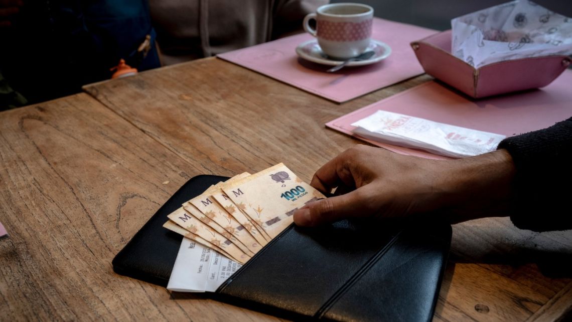 A server collects the bill at a cafe in Buenos Aires.