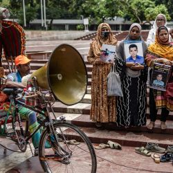 Un conductor de rickshaw lleva un altavoz mientras los familiares de las víctimas de desapariciones forzadas presuntamente cometidas por agencias gubernamentales durante el gobierno de la Liga Awami se reúnen sosteniendo pancartas y retratos de sus familiares desaparecidos mientras piden su regreso frente al Shaheed Minar en Dhaka, Bangladesh. | Foto:LUIS TATO / AFP