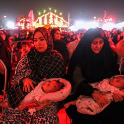 Las mujeres se sientan con sus bebés en brazos mientras asisten a la exposición "Moharram Shahr", antes de las conmemoraciones de Arbaeen que marcan el final del período de luto de 40 días por el asesinato en el siglo VII del nieto del profeta Mahoma, el imán Hussein ibn Ali, en la emblemática plaza Azadi en Teherán, Irán. | Foto:ATTA KENARE / AFP