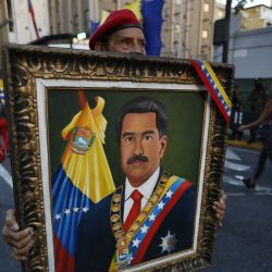 Un partidario del presidente Nicolás Maduro sostiene un retrato suyo durante una marcha para defender su supuesta victoria en las elecciones presidenciales en Caracas. | Foto:STRINGER / AFP