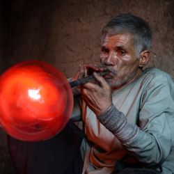 En esta fotografía Ghulam Sakhi Saifi, un soplador de vidrio afgano, elabora una pieza de vidrio en su taller tradicional en la ciudad de Herat, en el oeste de Afganistán. | Foto:Mohsen Karimi / AFP