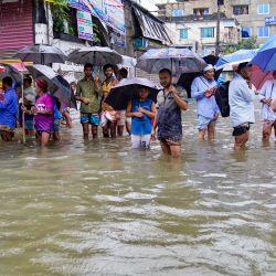 Personas con paraguas caminan por una calle inundada en medio de las lluvias en Feni, Bangladesh. | Foto:AFP