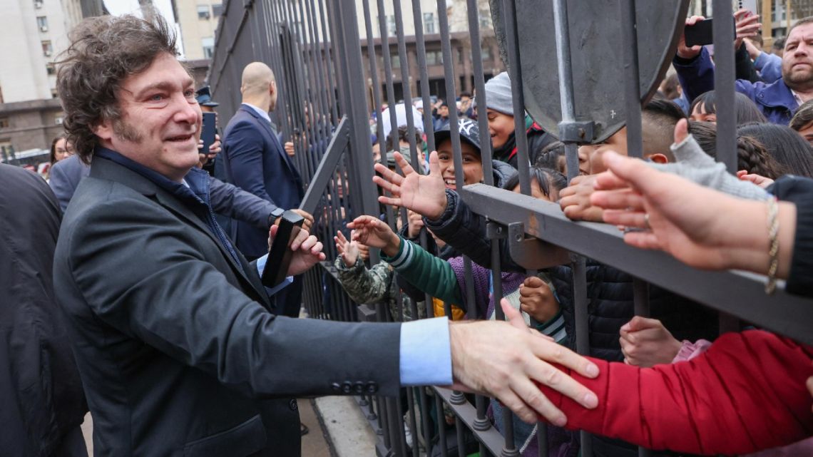 A handout photo released by the Presidency of President Javier Milei greeting schoolchildren through the fence of the Casa Rosada in Buenos Aires on August 20, 2024. 