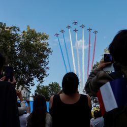 La gente toma imágenes del equipo de vuelo acrobático de élite de la Fuerza Aérea francesa "Patrouille de France" (PAF) lanzando estelas de humo con los colores de la bandera nacional francesa durante una ceremonia para conmemorar el 80 aniversario de la liberación de París de los alemanes en la Segunda Guerra Mundial, en París. | Foto:OLYMPIA DE MAISMONT / AFP