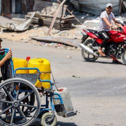 Un niño empuja una silla de ruedas cargada con bidones con agua por una calle en el centro de la ciudad de Gaza, en medio del conflicto en curso en el territorio palestino entre Israel y Hamás. | Foto:OMAR AL-QATTAA / AFP