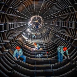 Los empleados trabajan en una línea de producción de torres de tubos de acero en una fábrica en Haian, en la provincia oriental china de Jiangsu. | Foto:AFP